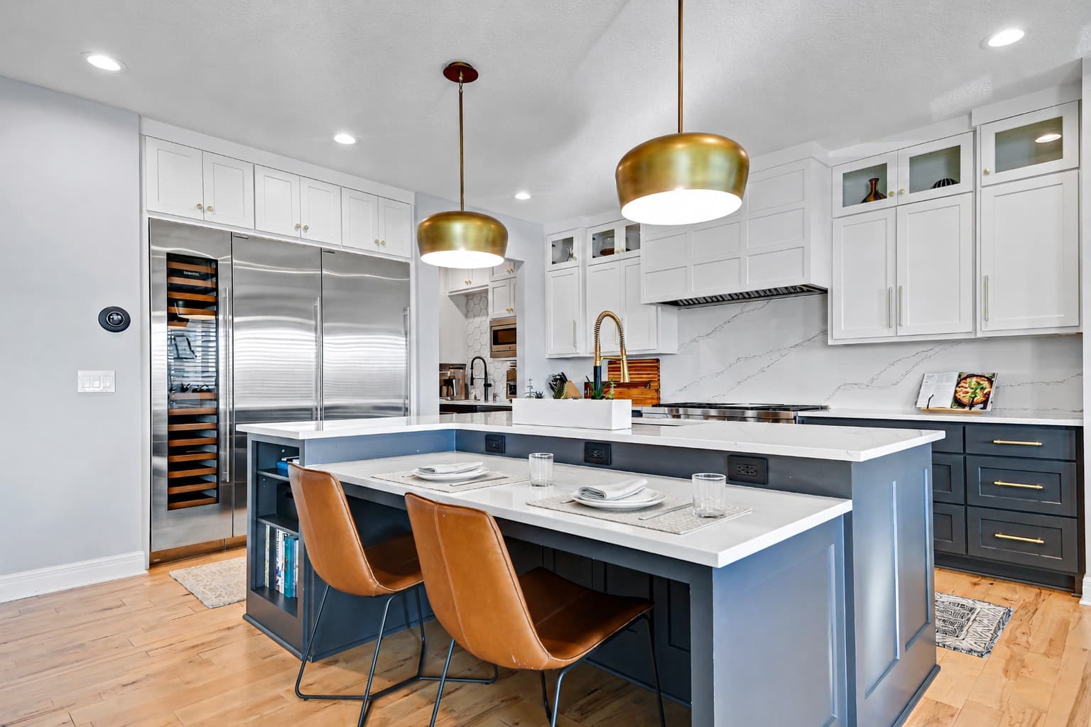 Kitchen with a deep blue island and brass pendants