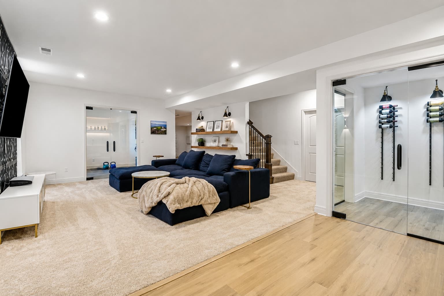 Lounge with navy sectional and a glass wine room